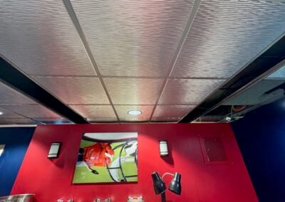 Red Feature Wall with a Framed Sports Photograph Two Wall Sconces and a Pair of Adjustable Black Lamps in a Blue walled Room