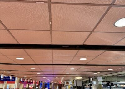 Spacious Airport Terminal with Check in Counters in the Distance Empty Brown tiled Floor and a Grid Ceiling with Recessed Lights