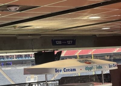 Dippin Dots Ice Cream Cart Under a White Umbrella in a Stadium Concourse with Empty Seating and Ceiling Tiles in the Background