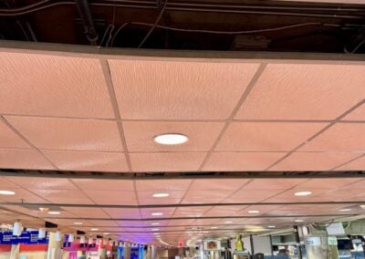 Ceiling with Exposed Wiring and Beige Tiles Recessed Lights View of a Busy Concourse in the Distance