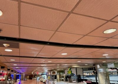 Long Indoor Concourse in an Airport Terminal with Shops Along the Right and a Grid Ceiling Above