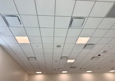 Ceiling with Square Grid Tiles Recessed Lights and Vents in a Large Room or Office Space