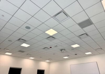 Ceiling with Grid of Square Tiles Recessed Lights Vents and a Whiteboard on the Right Wall in a Conference Room