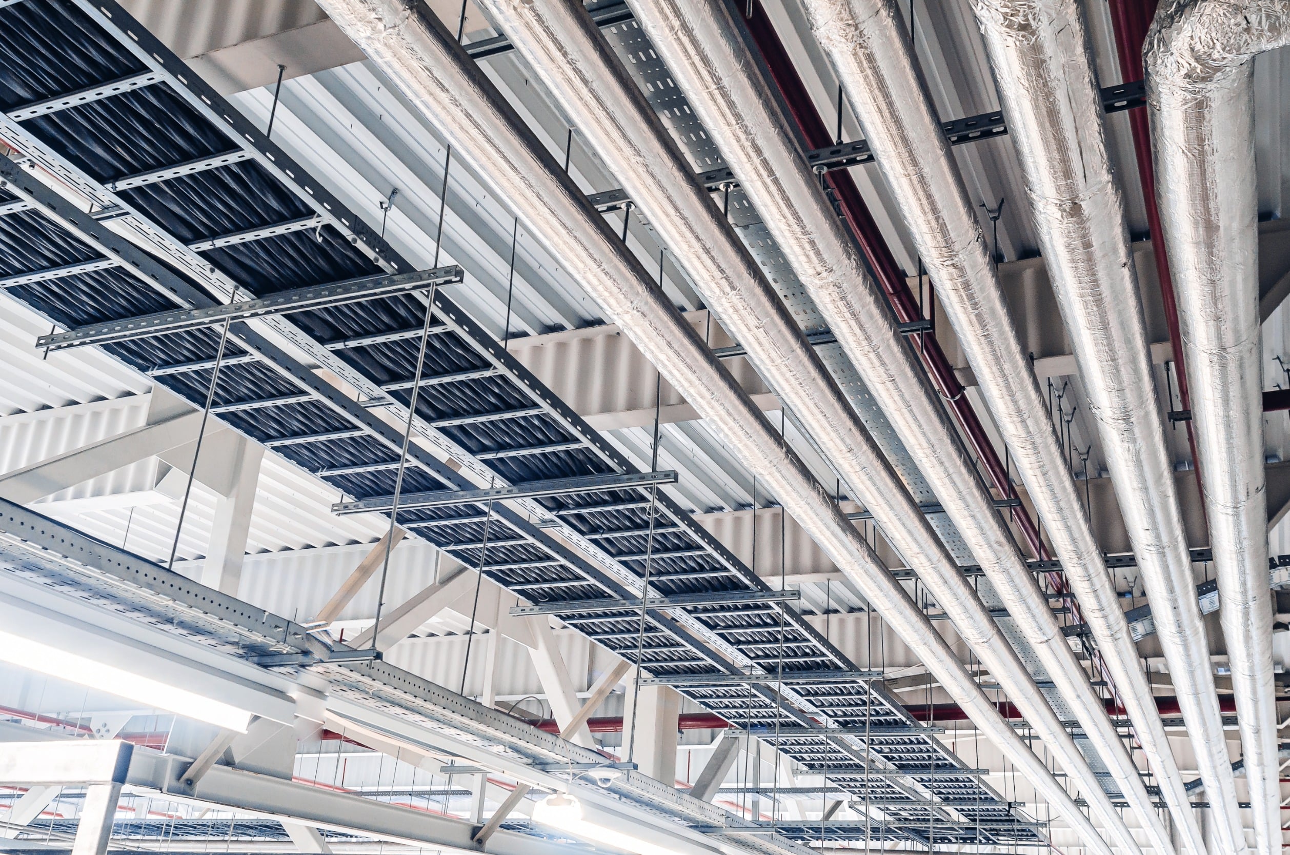 Commercial high-ceiling installation with exposed HVAC ducts, cable trays, and structural framing